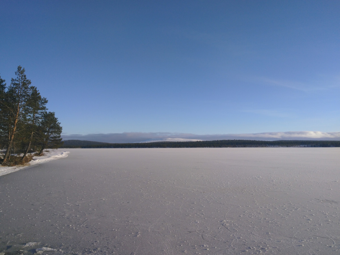 ice covered lake, blue sky, and snow covered fell in background